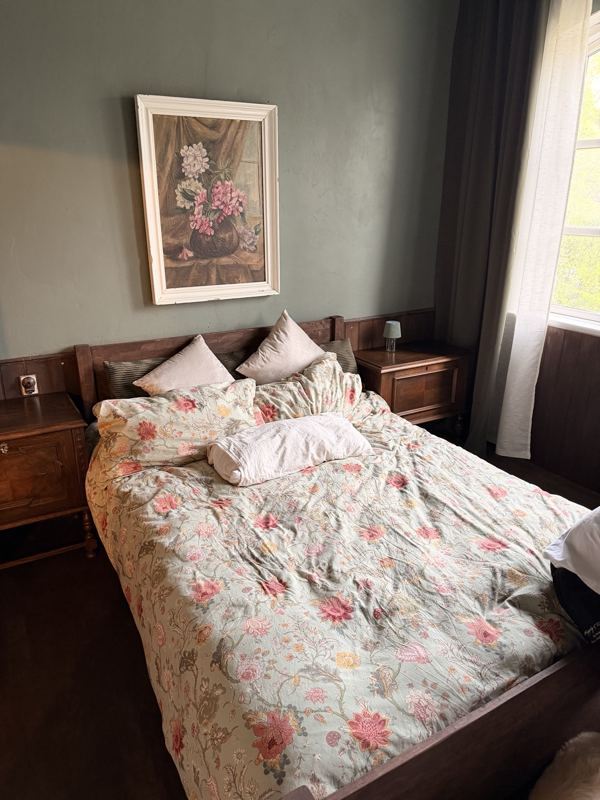 Doppelzimmer mit Holzbett und Blumenbettwäsche